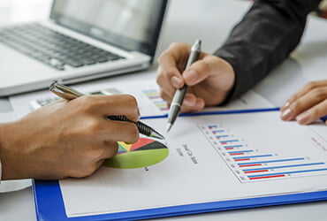 Two professional bookkeepers at Tax Purpose are reviewing financial charts and reports with a laptop, representing bookkeeping services in Melbourne